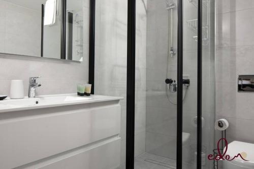 uma casa de banho branca com um chuveiro e um lavatório. em דירת 2 חדרי שינה עם נוף מדהים לים - By Edom em Eilat