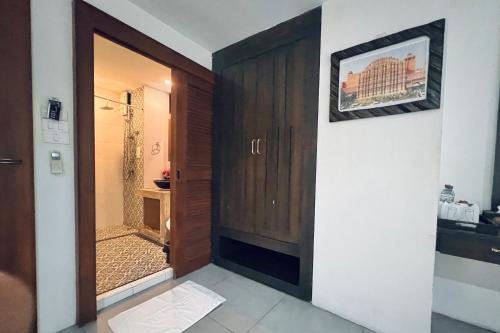 a bathroom with a shower and a wooden door at De Nawarat Chiangmai Boutique Apartment in Chiang Mai