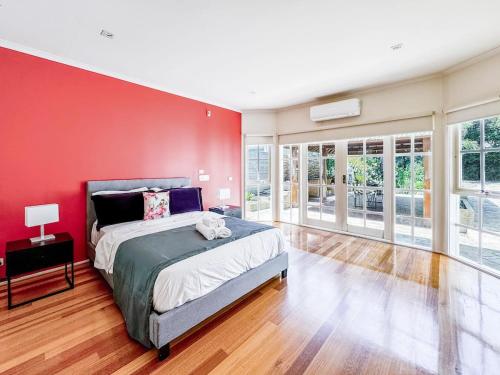 a bedroom with a red wall and a large bed at Elegant Bayside Retreat with Stunning Bay Views in Melbourne