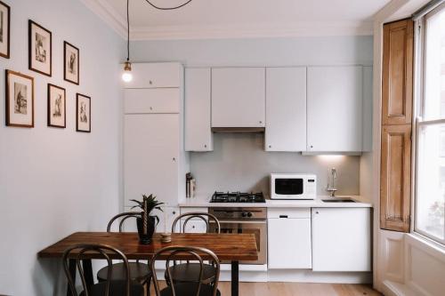 uma cozinha com armários brancos e uma mesa e cadeiras de madeira em Sapphire Sanctuary em Londres