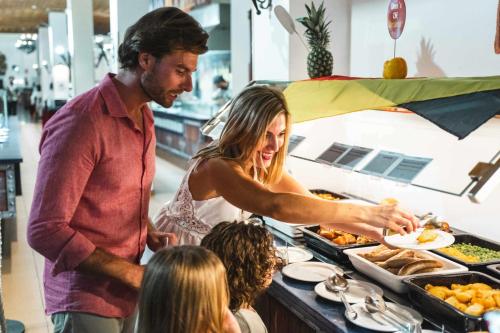 a man and a woman preparing food at a buffet at Magic Robin Hood in Albir