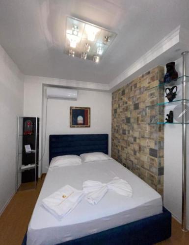 a bedroom with a bed with white sheets and a brick wall at ALBJONA GUESTHOUSE TIRANA in Tirana