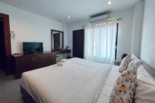 a bedroom with a white bed and a television at De Nawarat Chiangmai Boutique Apartment in Chiang Mai