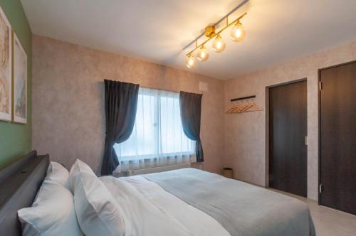 a bedroom with a large white bed and a window at Rusutsu Grand Cabin - Vacation STAY 16626v in Kimobetsu