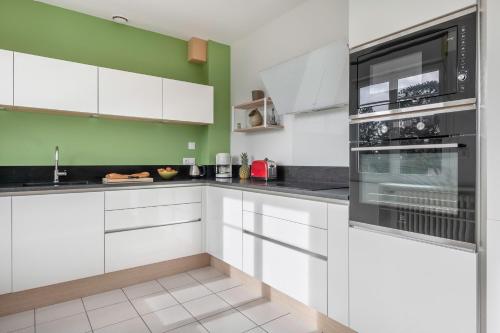 une cuisine avec des armoires blanches et des appareils noirs dans l'établissement Détente tout près de la plage de Sainte-Marguerite, à Pornichet