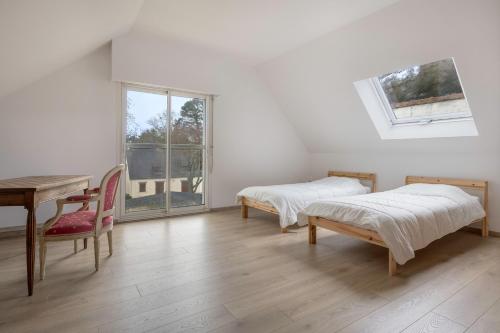 a room with two beds and a table and a window at Détente tout près de la plage de Sainte-Marguerite in Pornichet