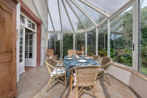 - une salle à manger avec une table et des chaises dans une véranda dans l'établissement Maison pour 6 à la Bernerie à 270m de la plage, à La Bernerie-en-Retz
