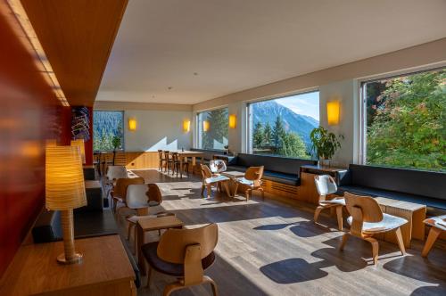 ein Restaurant mit Tischen und Stühlen und großen Fenstern in der Unterkunft Valbella-Lenzerheide Youth Hostel in Lenzerheide