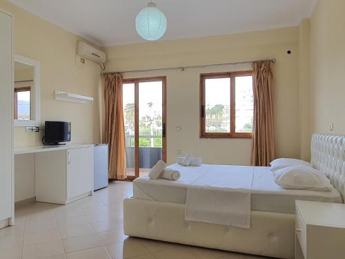 Un dormitorio con una gran cama blanca y una cocina. en Mintt Hotel, en Ksamil