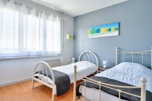 deux lits dans une chambre aux murs bleus dans l'établissement Séjour au coeur de l'Île-de-Noirmoutier, à Noirmoutier-en-l'lle