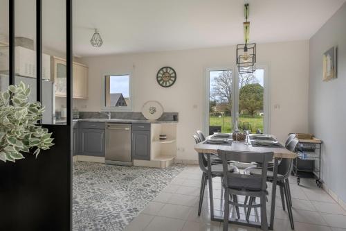 une cuisine avec une table et des chaises dans une pièce dans l'établissement Maison moderne pour 5 - 950m des marais, à Saint-Molf