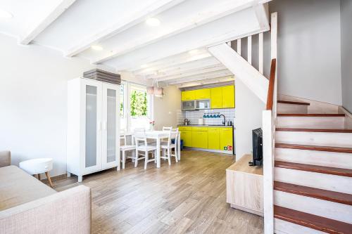 a kitchen and dining room with yellow cabinets and a staircase at Bedroom - domek nr 2 in Łeba