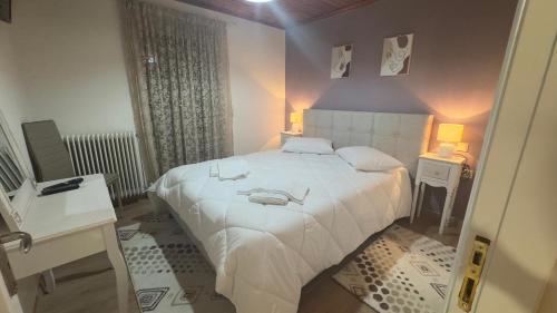 a bedroom with a large white bed and two tables at GUESTHOUSE ''ΧΡΥΣΑ'' in Dhimitsana