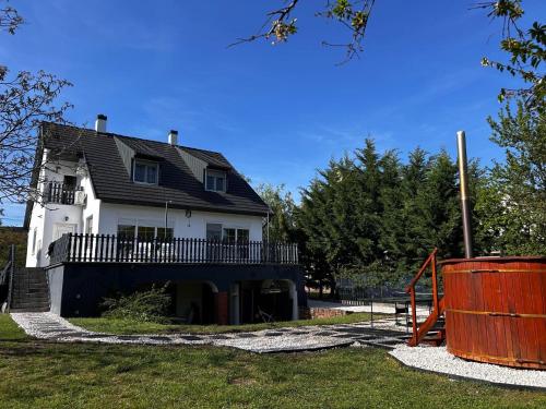 a large white house with a porch and a playground at Sunny Beach in Zánka
