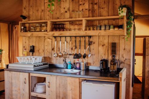 a kitchen with wooden walls and a counter with a sink at Glamping-tent 'Yatra Nirvana' met privé keuken en regendouche in Grou