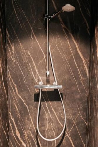 a shower in a bathroom with a marble wall at Vakantiewoning Domein Hooverbosch in Zonnebeke