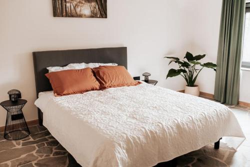 1 dormitorio con 1 cama blanca grande con almohadas de color naranja en Vakantiewoning Domein Hooverbosch en Zonnebeke