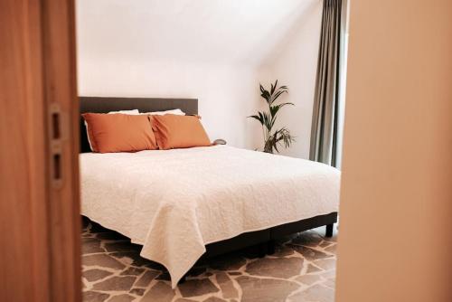 a bedroom with a bed with orange pillows on it at Vakantiewoning Domein Hooverbosch in Zonnebeke