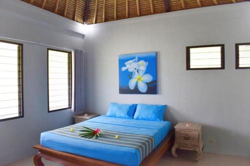 a bedroom with a blue bed in a room with windows at Pandana Boutique Hotel in Nusa Lembongan