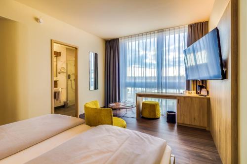 ein Hotelzimmer mit einem Bett, einem Schreibtisch und einem TV in der Unterkunft Lagovida Das Ferienresort Am Störmthaler See in Großpösna