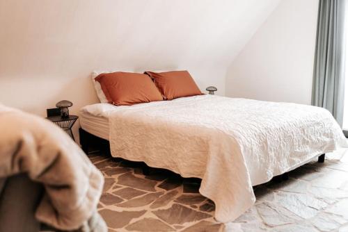 a bedroom with a large bed with orange pillows at Vakantiewoning Domein Hooverbosch in Zonnebeke