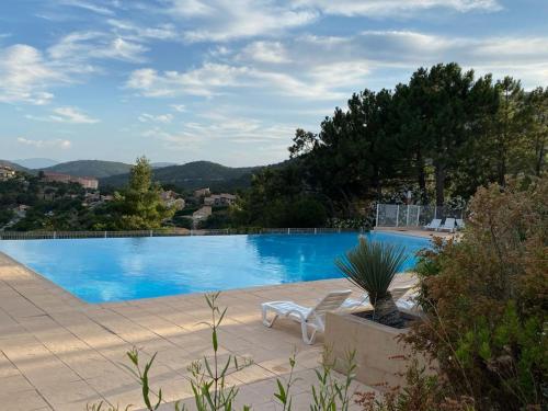 - une piscine bleue avec une chaise blanche à côté dans l'établissement Le PTIT PARADIS, piscine - tennis, aux Issambres