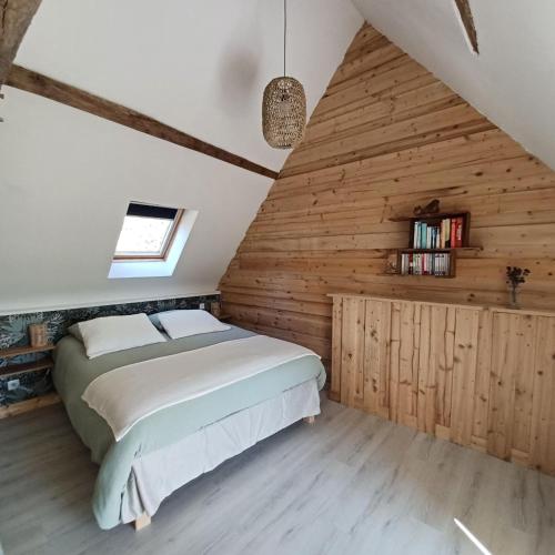 une chambre avec un lit et un mur en bois dans l'établissement Maison en lisière de forêt, à Panzoult