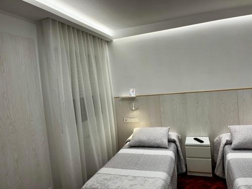 a small room with two beds and a window at Hostal Charo II in Santiago de Compostela