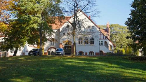 a large white house with cars parked in front of it at Parkresidenz Lychen, Ferienwohnung 10 in Lychen