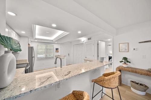 una cucina con pareti bianche e bancone con sgabelli di Loggerhead Cay #401 a Sanibel