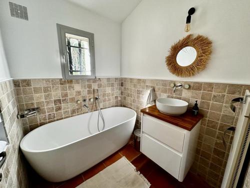 a bathroom with a tub and a sink and a mirror at Le Mas Miliane vous accueille in Sainte-Maxime