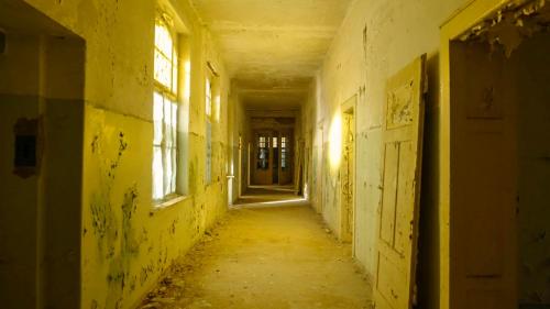 an empty hallway in an old building with yellow walls and windows at Parkresidenz Lychen, Ferienwohnung 5 in Lychen