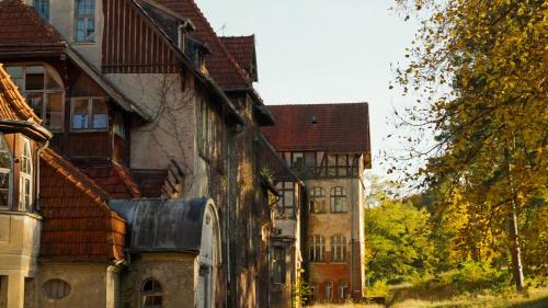 an old house with a building in the background at Parkresidenz Lychen Ferienwohnung 2 in Lychen