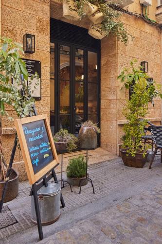 a sign in front of a building with plants at Boutique Hotel Casa Cánovas in Cádiz