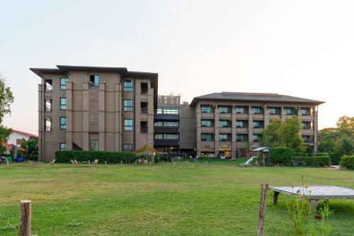 un gran edificio con un parque enfrente en Blu Monkey Brown House Udonthani, en Udon Thani