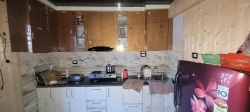 uma pequena cozinha com armários de madeira e um frigorífico em POP Home Zohan Homestay em Jamu