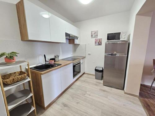 una cucina con armadi bianchi e frigorifero in acciaio inossidabile di Dj apartment Kostrena a Šodići