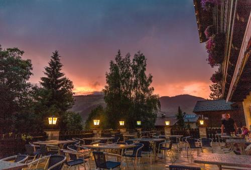 a patio with tables and chairs with a sunset in the background at Hotel Kirchboden by Alpeffect Hotels in Wagrain
