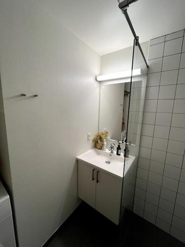 a white bathroom with a sink and a mirror at Moderne lejlighed i hjertet af Odense C in Odense