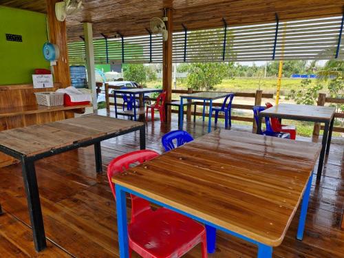 a restaurant with wooden tables and colorful chairs at Yungthong Baan Suan Resort in Ban Ko