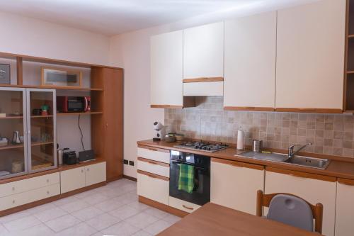 a kitchen with white cabinets and a wooden table at The River Nest in Lasnigo