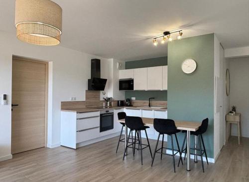 une cuisine avec une table et des chaises dans une pièce dans l'établissement Superbe appartement neuf 4pers, à LʼÎle-Rousse