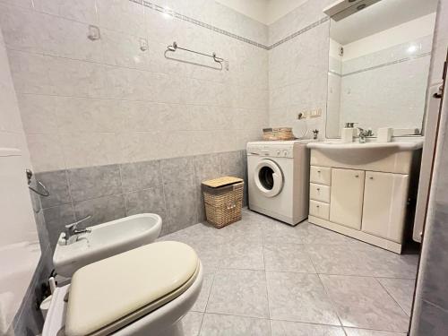 a bathroom with a toilet sink and a washing machine at Posta Vecchia in Grado