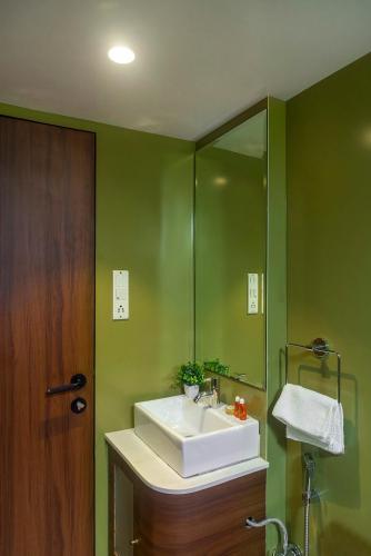a green bathroom with a sink and a mirror at Hotel Orritel West in Mumbai