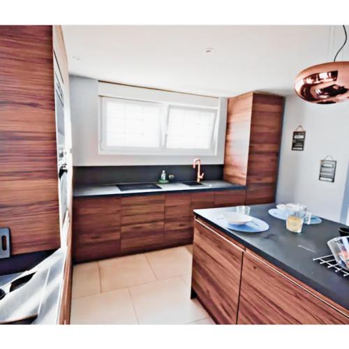 une cuisine avec des armoires en bois, un évier et une fenêtre dans l'établissement STNAHOME 60110 Maison Champêtre aux Portes de Paris, à Amblainville