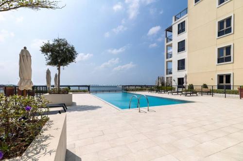 a swimming pool in front of a building at Goldbest La Mer - Luxury 1 bdr Apartment with Beachfront Pool in Dubai
