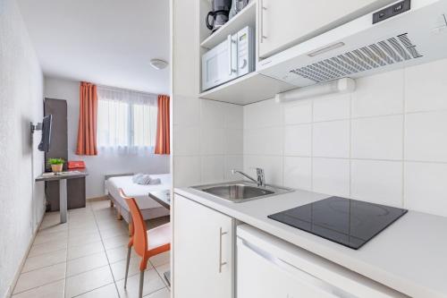 uma cozinha com um lavatório e um quarto com uma cama em Appart'City Classic Marseille Aéroport - Vitrolles em Vitrolles