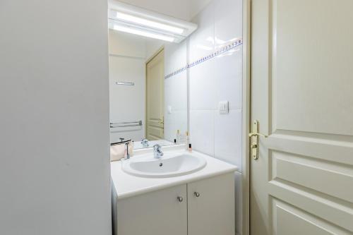 a white bathroom with a sink and a mirror at Appart'City Classic Marseille Aéroport - Vitrolles in Vitrolles