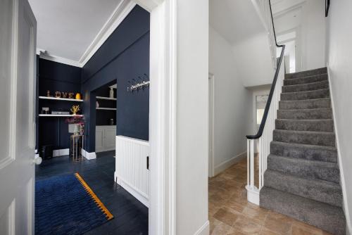 a hallway with stairs and a blue wall at The Executive - Central Plymouth House - Sleeps 9 - Habita Property in Plymouth