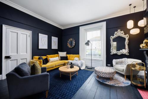 a living room with blue walls and a yellow couch at The Executive - Central Plymouth House - Sleeps 9 - Habita Property in Plymouth